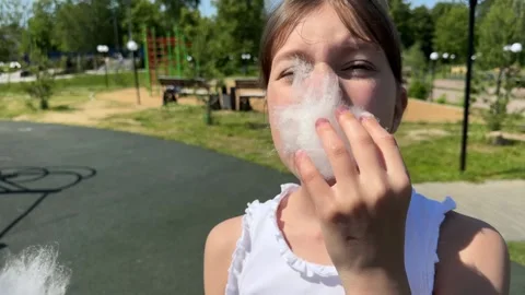 A happy child eats sweet cotton candy at an amusement park on a summer day, Stock Footage 244326482