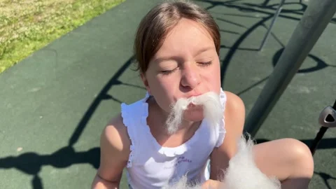 A happy child eats sweet cotton candy at an amusement park on a summer day, Stock Footage 244326596
