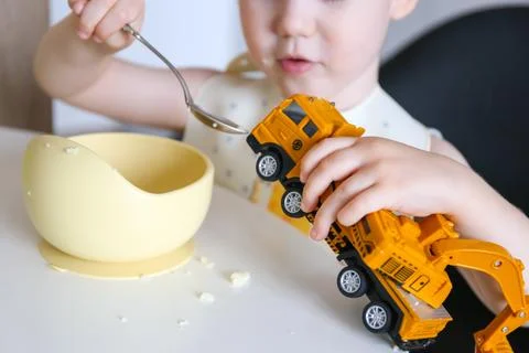 Happy child eats at the table on his own. Healthy food, the boy feeds the c.. Stock-Fotos