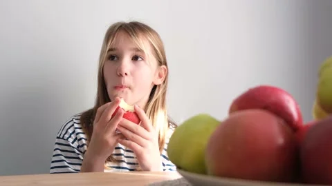 Happy child girl eats red apple, healthy food, girl eats fruit. Vegetarianism in Video stock 212464280