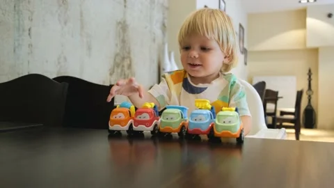Happy child has fun playing with a colorful car at table in a restaurant Stock Footage 201461210