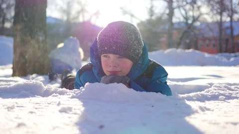 Happy child having fun in winter Park on a Sunny day.Lying in the snow 動画素材 70701679