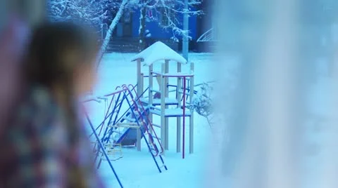 Happy child looking out the window at the snow-covered playground Video stock 20497708