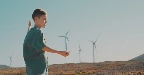 Happy child on looking at wind energy turbine sat wind farm site Stock Footage 234424897