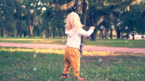 Happy child play with soap bubbles in spring park. Slow motion Stock Footage 95727708