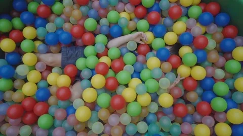 Happy child playing at colorful plastic balls playground high view Stock Footage 79099403