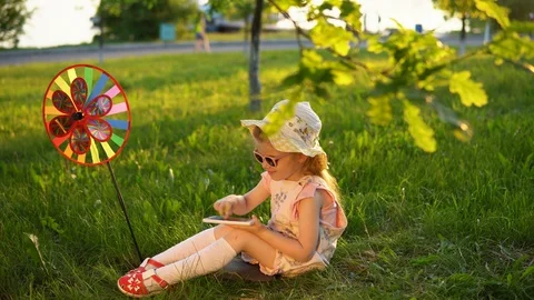 Happy child playing on grass under young oaks in a public park at sunset. Stock Footage 92456750