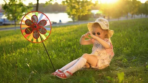 Happy child playing on grass under young oaks in a public park at sunset. Stock Footage 94183867