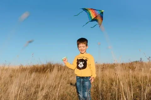 Happy child playing with a kite while running on meadow, sunset, in summer .. Stock Photos