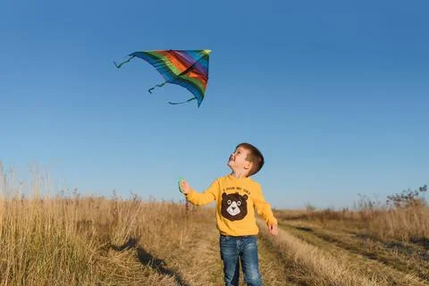Happy child playing with a kite while running on meadow, sunset, in summer .. Foto stock
