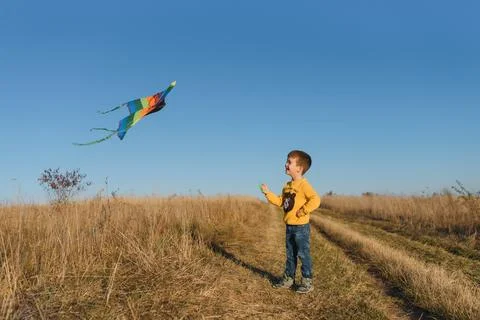 Happy child playing with a kite while running on meadow, sunset, in summer .. Stock Photos