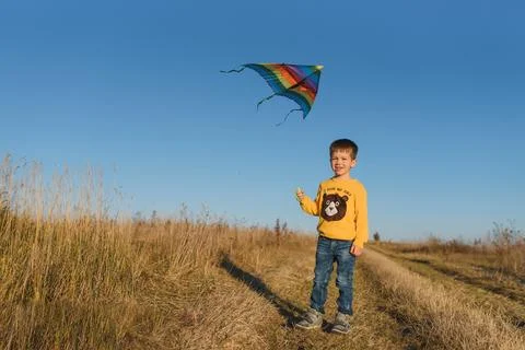 Happy child playing with a kite while running on meadow, sunset, in summer .. Stock Photos
