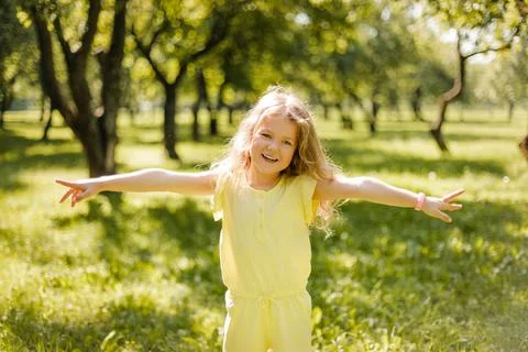 A happy child playing in a summer park. The girl is running, spinning, spinning Stock Photos