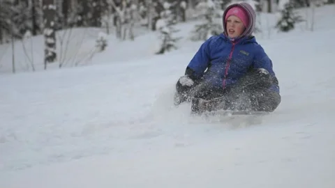 Happy child rides a sled down a snowy slope. Slow motion Stock Footage 328240361