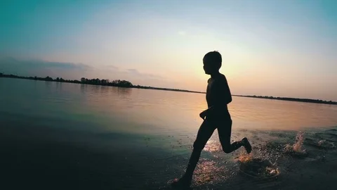 Happy Child Runs Along the Beach at Sunset. Slow Motion Stock Footage