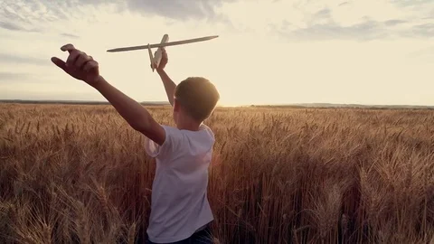 Happy child runs with a toy airplane on a sunset background over a wheat field Stock Footage