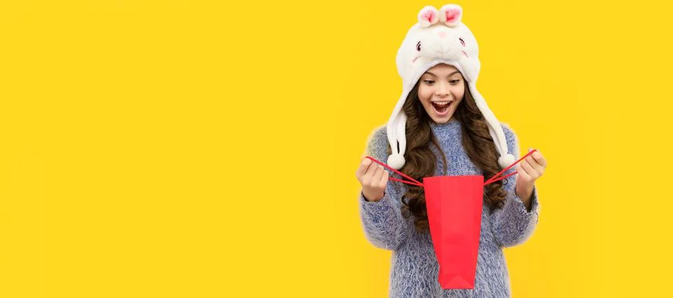 Happy child in sweater and hat hold shopping bag on yellow background, xmas Stock Photos