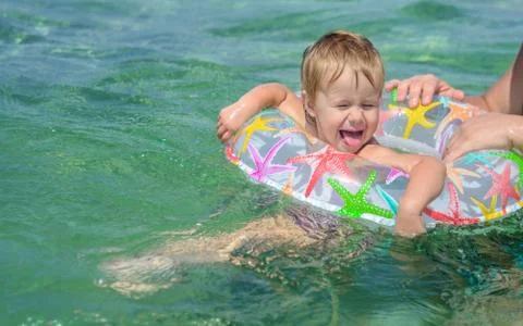 Happy child swimming in bright inflatable circle  in the sea. Stock Photos