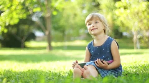 Happy child with a tablet pc sitting on the grass. Thumbs up. Ok Video stock 11858868