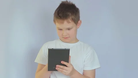 Happy child using tablet pc. Boy with tablet computer at white background. Teen Stock-Footage 99859905