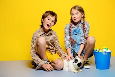 Happy children are posing with Easter attributes on yellow  background. Happy Stock Photos
