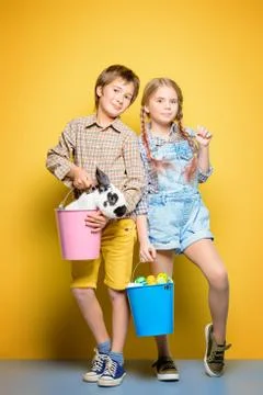 Happy children are posing with Easter attributes on yellow  background. Happy Stock Photos
