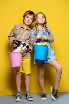 Happy children are posing with Easter attributes on yellow  background. Happy Stock Photos