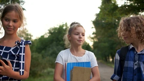 Happy children come back from school and laugh cheerfully. Carry books and a big Video stock 114018897