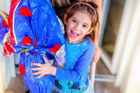 Happy children easter egg background - little girl smiles embracing big easter Stock Photos