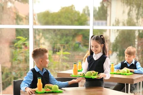 A group of cheerful small school kids in canteen, eating lunch. Stock Photo