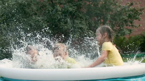 Happy children jump in an round pool on hot summer day, splash and have fun Stock Footage 204155237