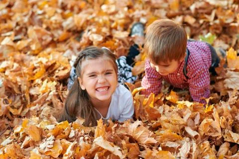 Happy children playing, posing, smiling and having fun in autumn city park. B Stock Photos