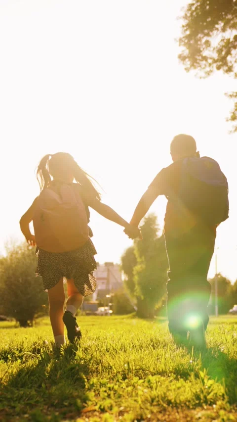 Happy children with school backpacks running hands along green lawn sunset Stock Footage 268746292