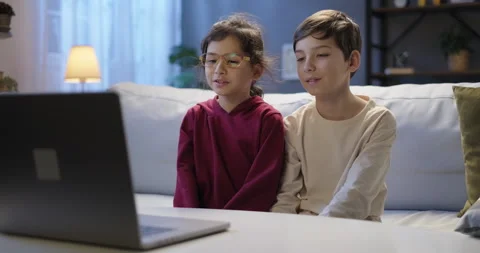Happy children using laptop talking by webcam with friends or relatives in Stock Footage 265610642