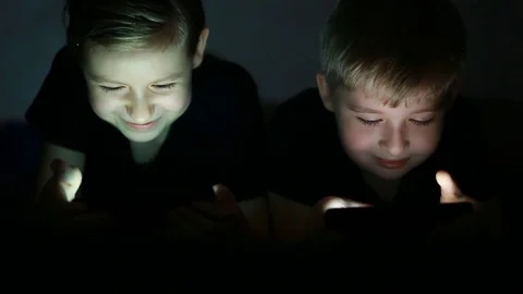 Happy children using smart phone together browsing online. Boy and girl at ho Stock Footage