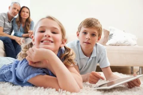 Happy children using a tablet computer with their parents on the background Stock Photos
