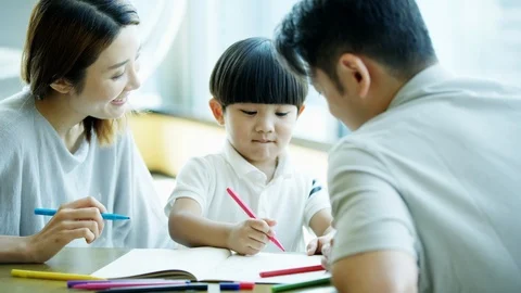 Happy Chinese Asian boy colouring pictures with parents Stock Footage