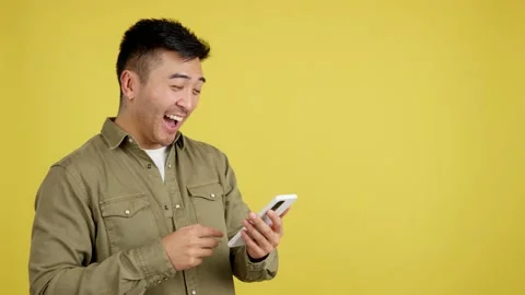 Happy chinese man smiling while using the mobile Stock Footage 233523322