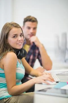 Happy classmates doing an assignment together in the computer room Stock Photos