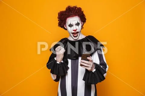 Happy clown using smartphone and making winner gesture Stock Photos