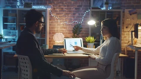 Happy colleagues smartphone app developers discussing work in dark office Stock Footage 118617427