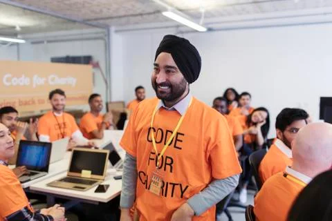 Happy, confident hacker in turban coding for charity at hackathon 스톡 사진