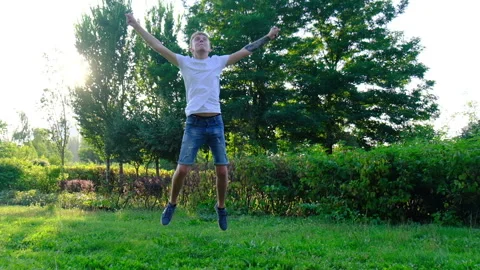 Happy contented guy bouncing up on natural background Stock Footage 119443275