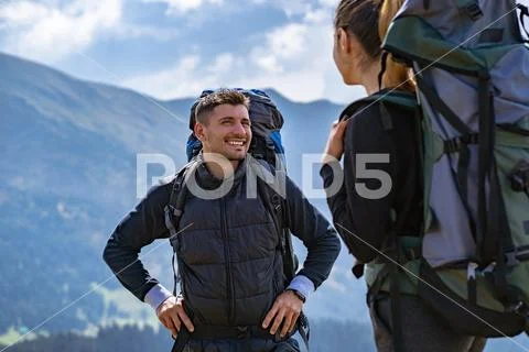 The happy couple with backpacks standing on the mountain landscape background Stock Photos