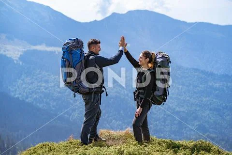 The happy couple with backpacks standing on the mountain landscape background Stock Photos