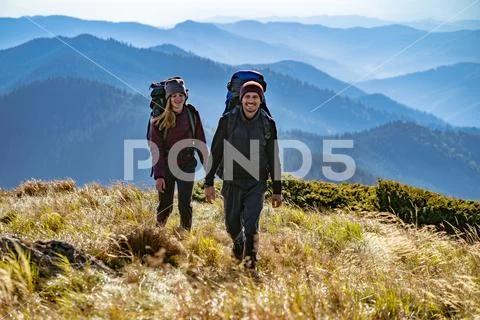 The happy couple with backpacks walking to the mountain Stock Photos