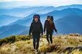The happy couple with backpacks walking to the mountain Photo