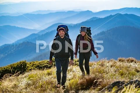 The happy couple with backpacks walking to the mountain Stock Photos