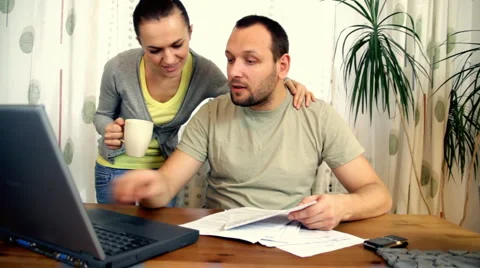 Happy couple with bills and laptop Stock Footage