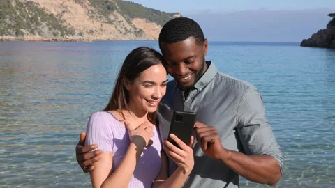 Happy couple checking smart phone on the beach Stock Footage 173111356